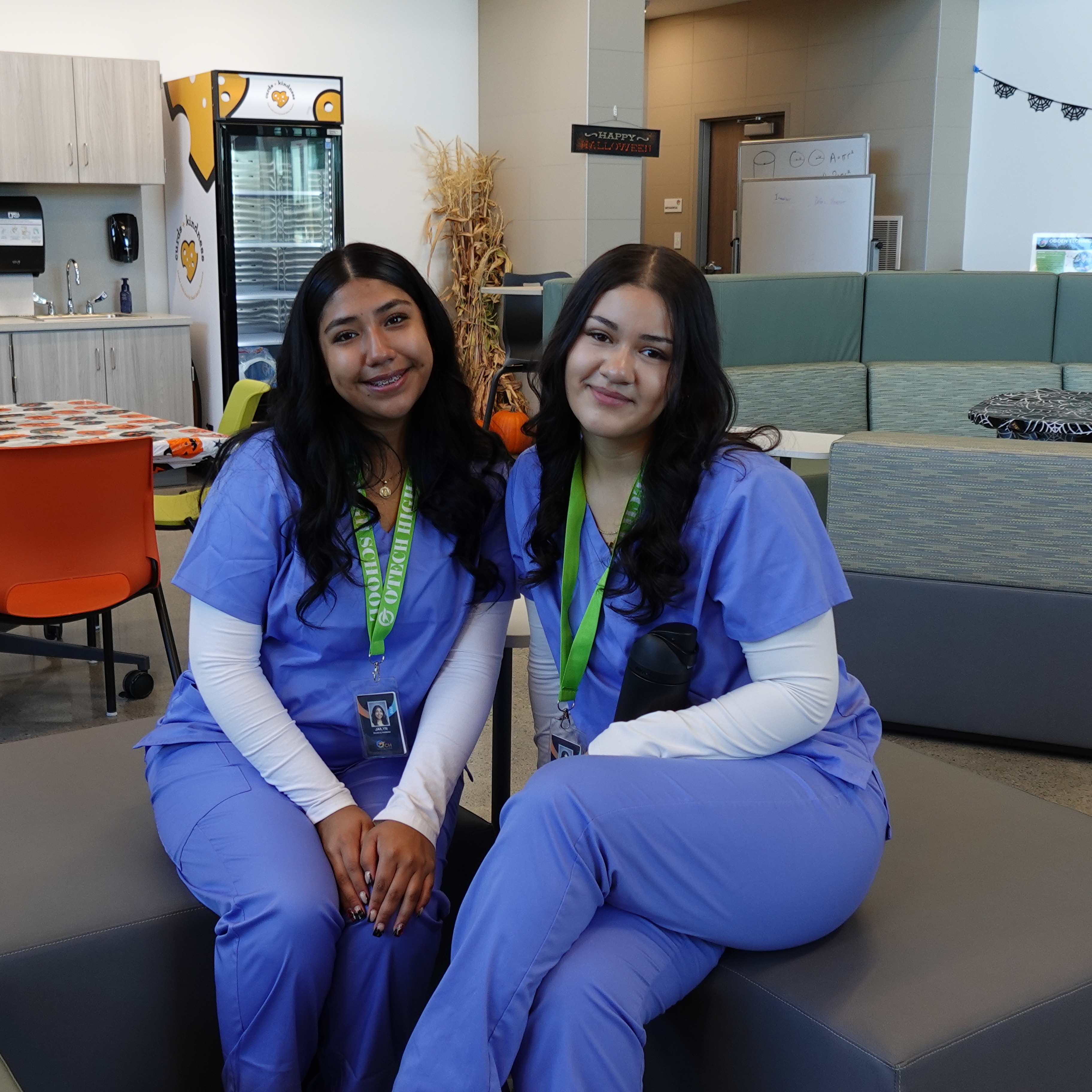 two otech students sitting with their scrubs on 