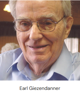 An elderly man with gray hair, wearing a light blue shirt, sitting indoors, likely at a social gathering.