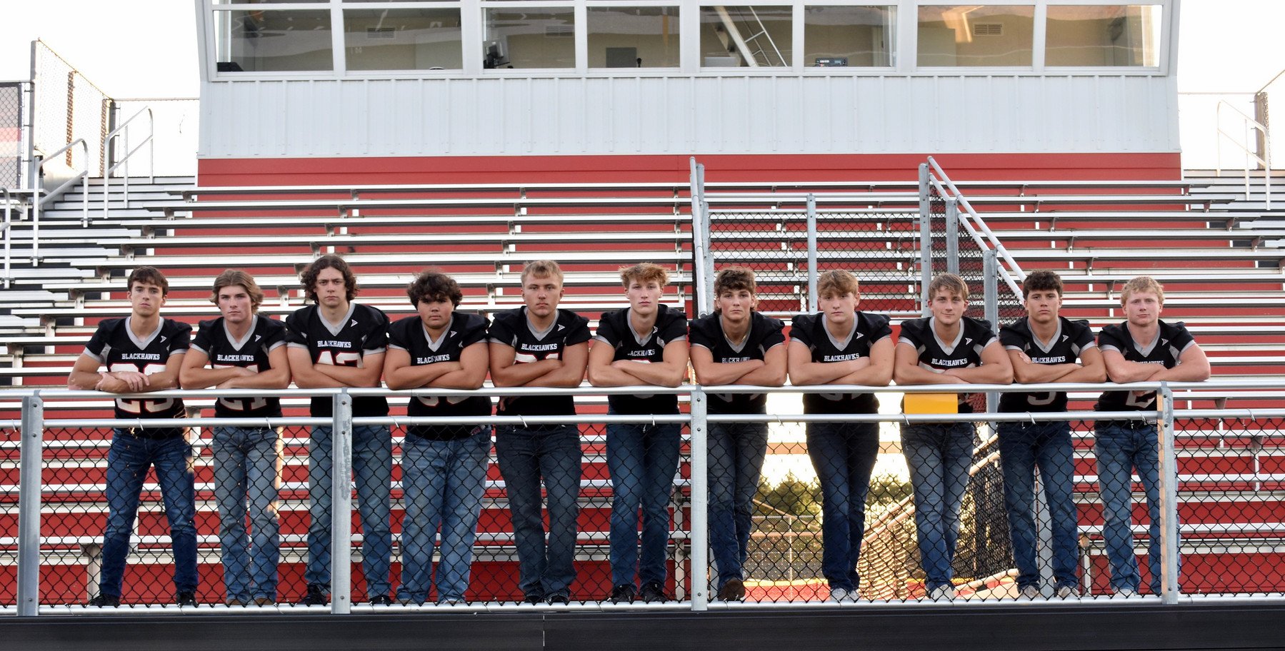 Football team standing along railing.