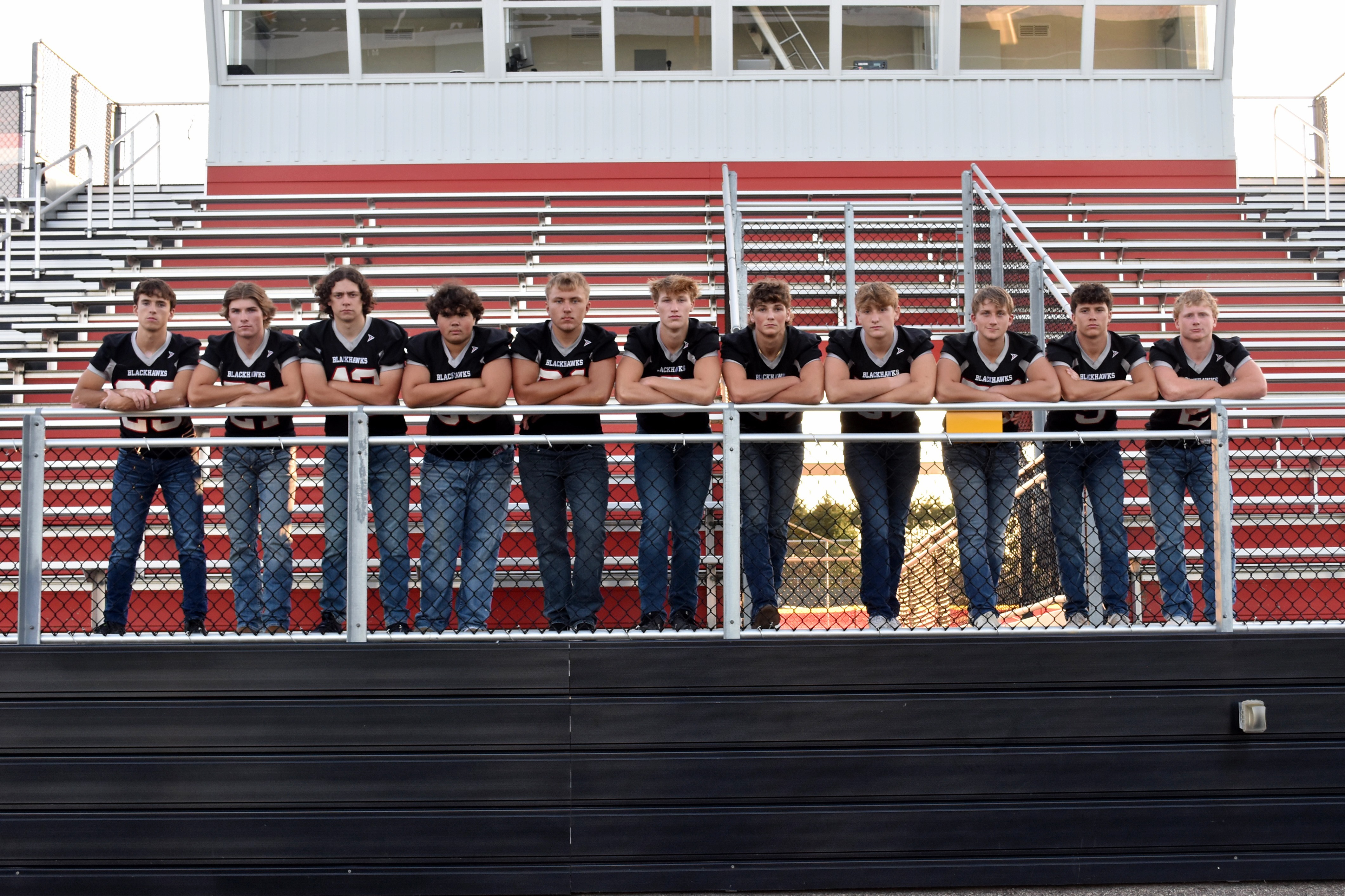 High School Football Team leaning on bleacher railing.