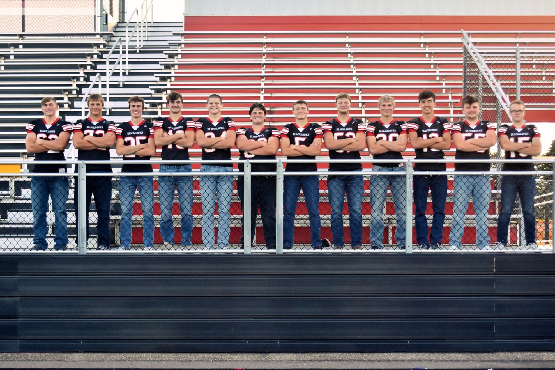 High School Football Team leaning on bleacher railing.