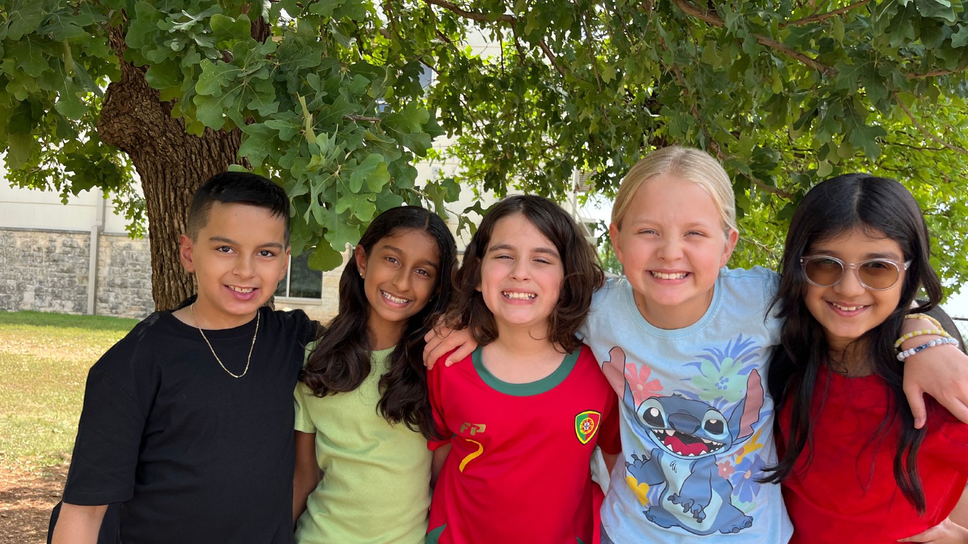 Group of children smiling outside at recess