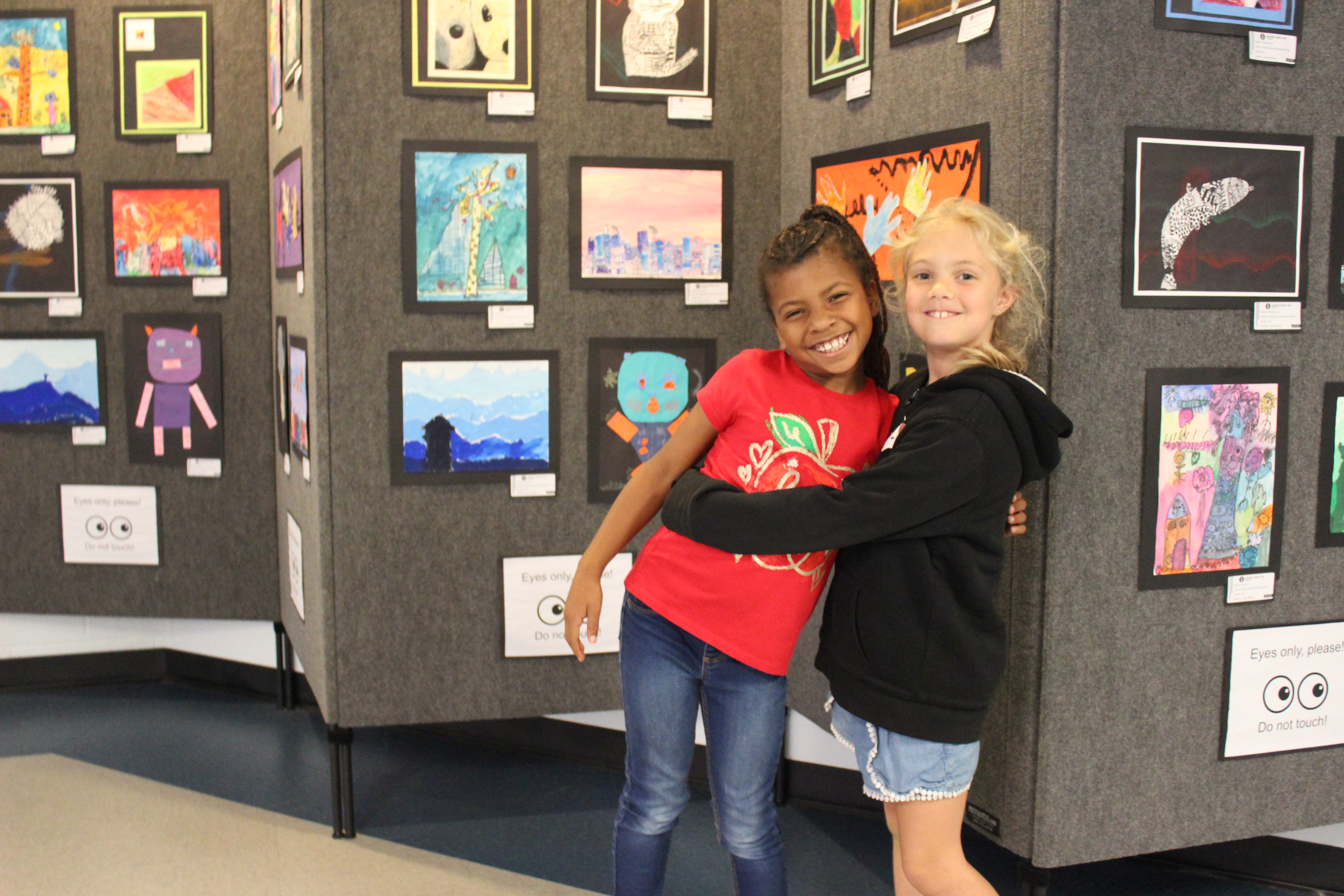 Students beside a display of student artwork