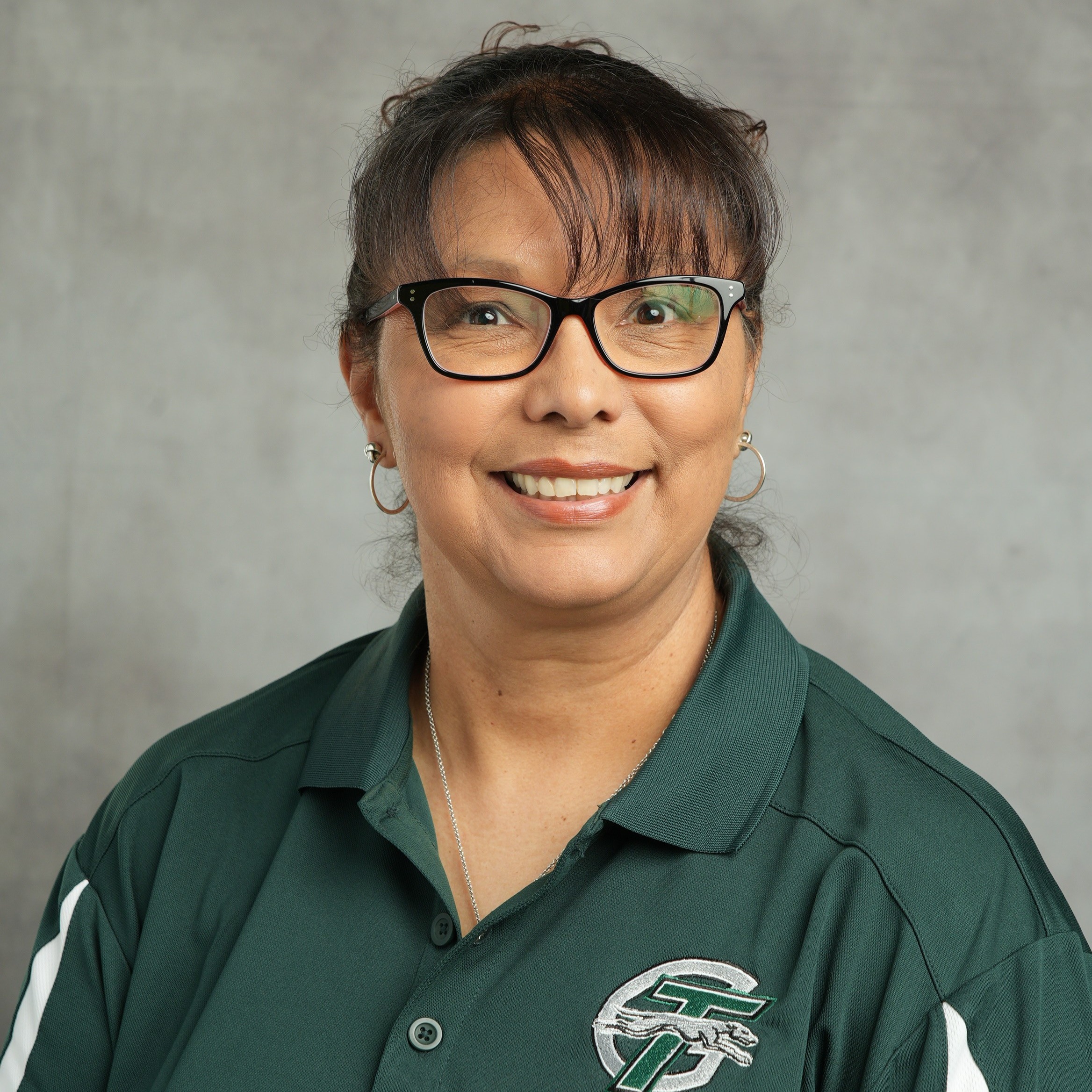 A woman wearing a green shirt stands confidently against a vibrant blue background.