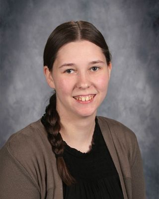 A young woman with a braid in her hair, smiling softly against a neutral background.