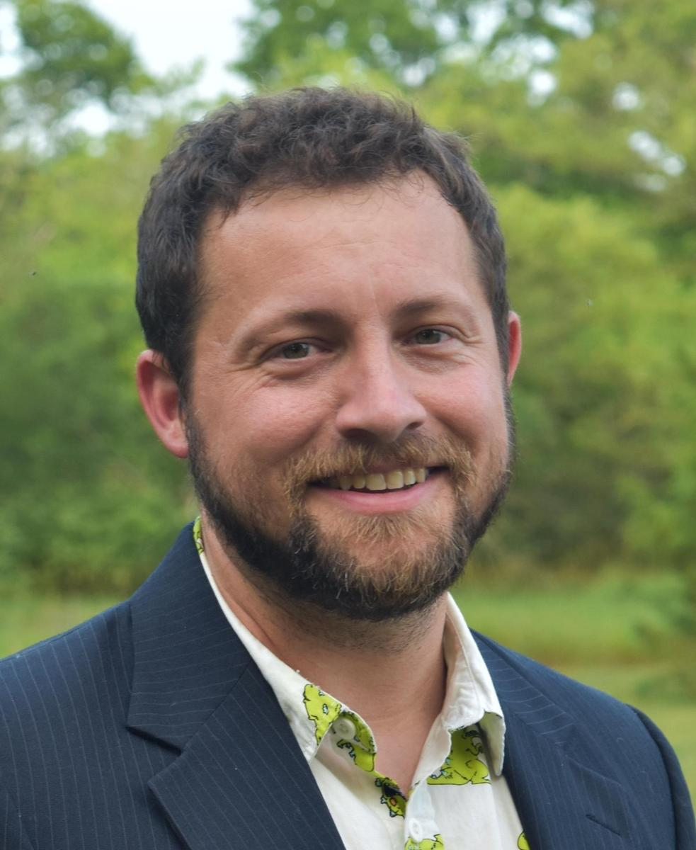 A smiling man with a beard wearing a green shirt.
