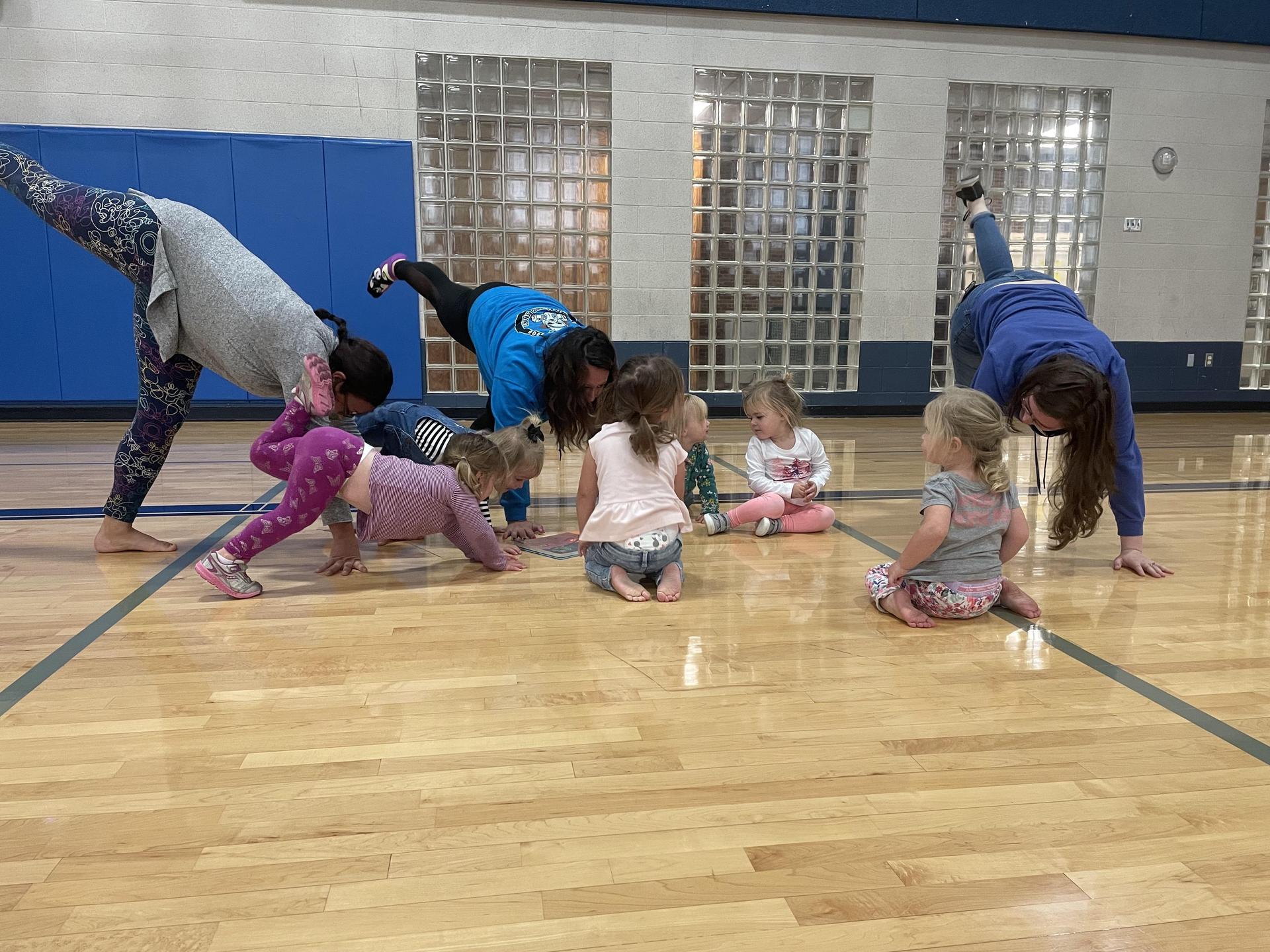 A group of children practicing yoga poses together in a bright gym environment, promoting fitness and mindfulness.
