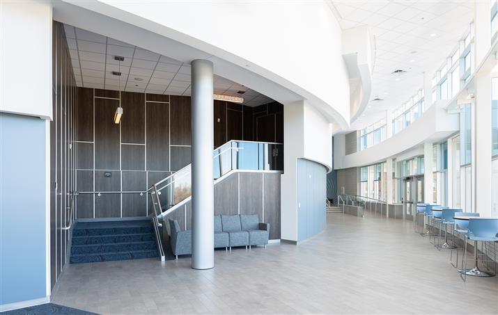 A spacious hallway featuring blue chairs and a prominent staircase, creating an inviting atmosphere.