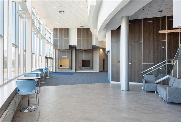 A spacious hallway featuring blue chairs and a prominent staircase, creating an inviting atmosphere.