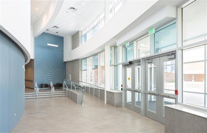A spacious hallway featuring blue chairs and a prominent staircase, creating an inviting atmosphere.