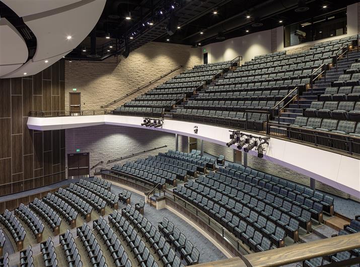 A spacioA spacious hallway featuring blue chairs and a prominent staircase, creating an inviting atmosphere.us auditorium featuring rows of empty seats facing a well-lit stage, ready for an upcoming event.