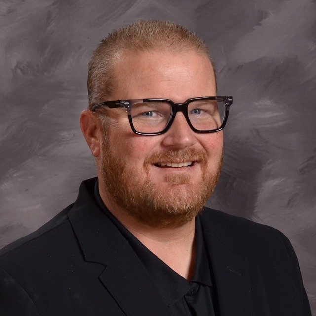 A library illuminated by green lights, featuring rows of bookshelves filled with various books.