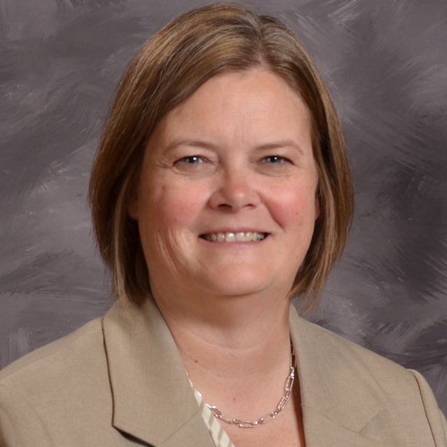 A woman wearing a black shirt and a necklace, exuding elegance and confidence in her appearance.