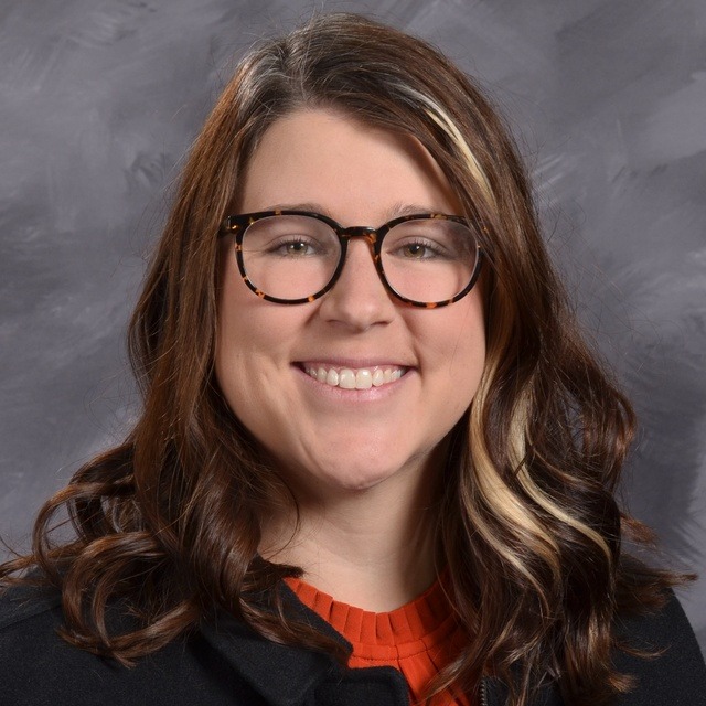 A girl wearing a cozy sweater and earrings, smiling brightly, radiating warmth and joy.