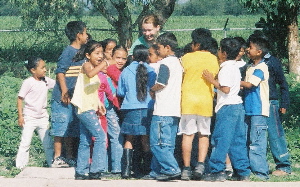 A group of children gathered around a wooden fence, engaging in conversation and enjoying their time together outdoors.