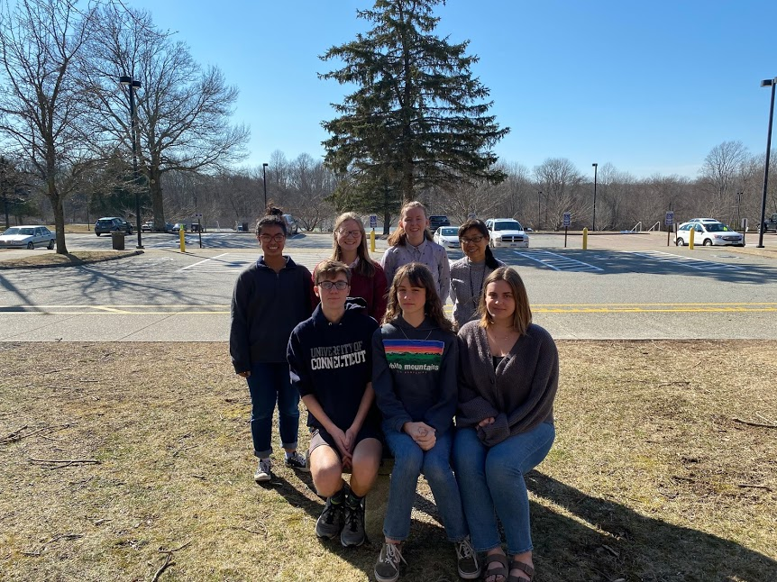 A group of students smiling and posing together in front of a parking lot, capturing a moment of camaraderie.