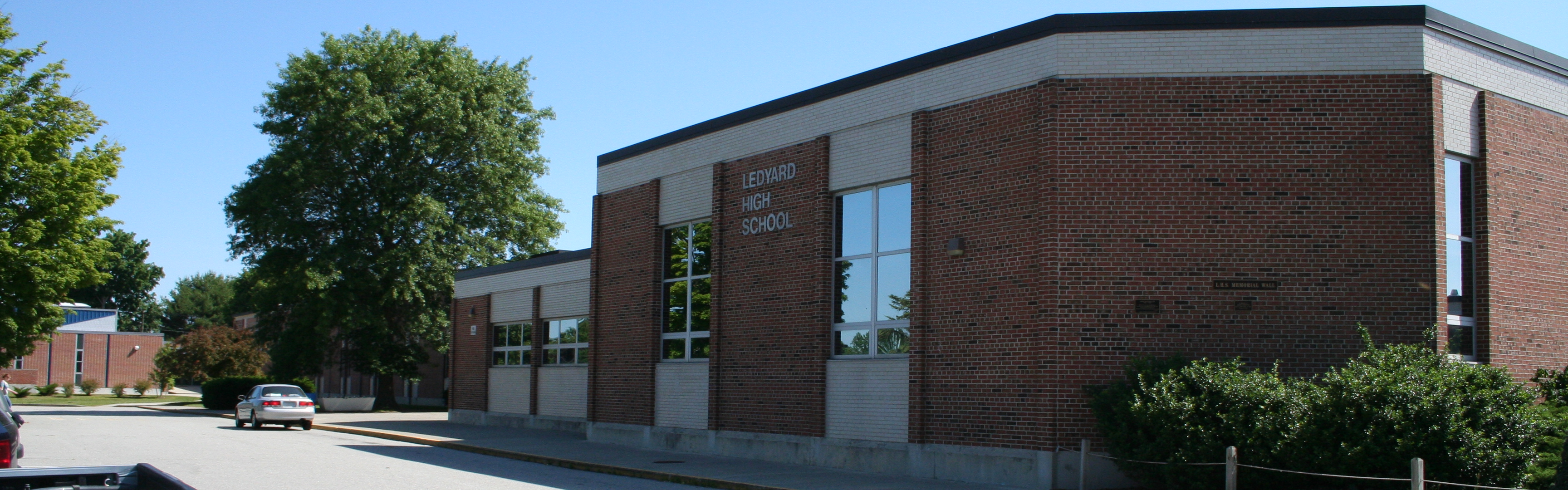 A brick school with a large, green tree under a very blue sky
