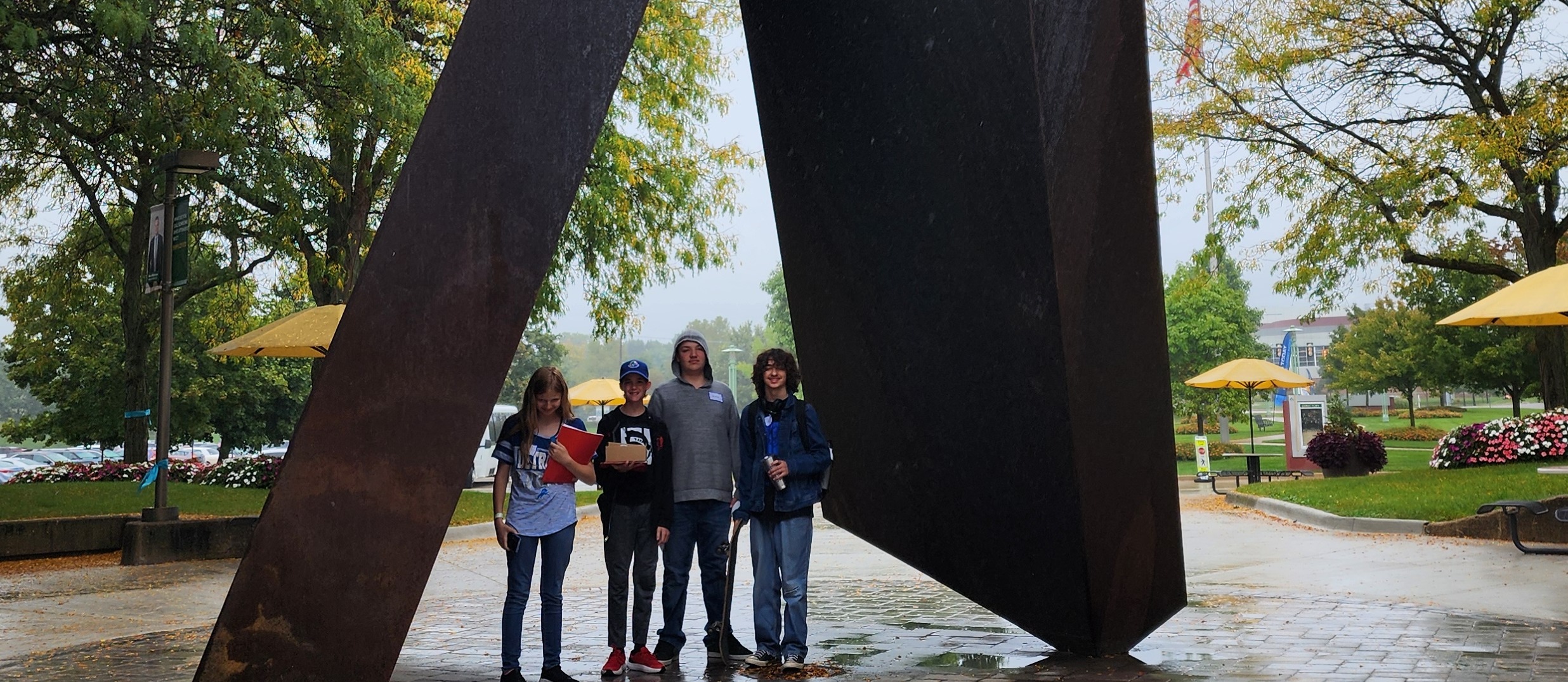 Photo of 4 students posing in front of a sculpture during field trip.