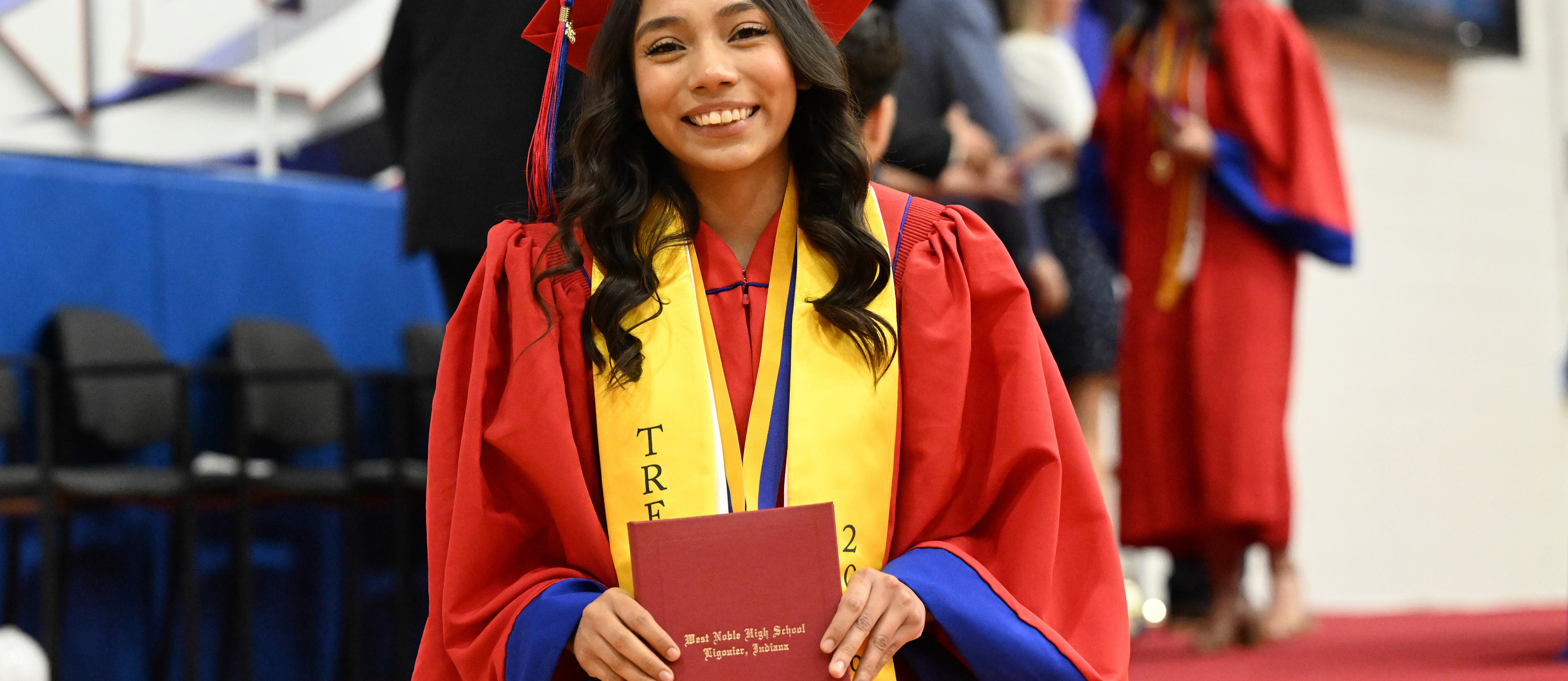 a graduate in a red gown holding a diploma