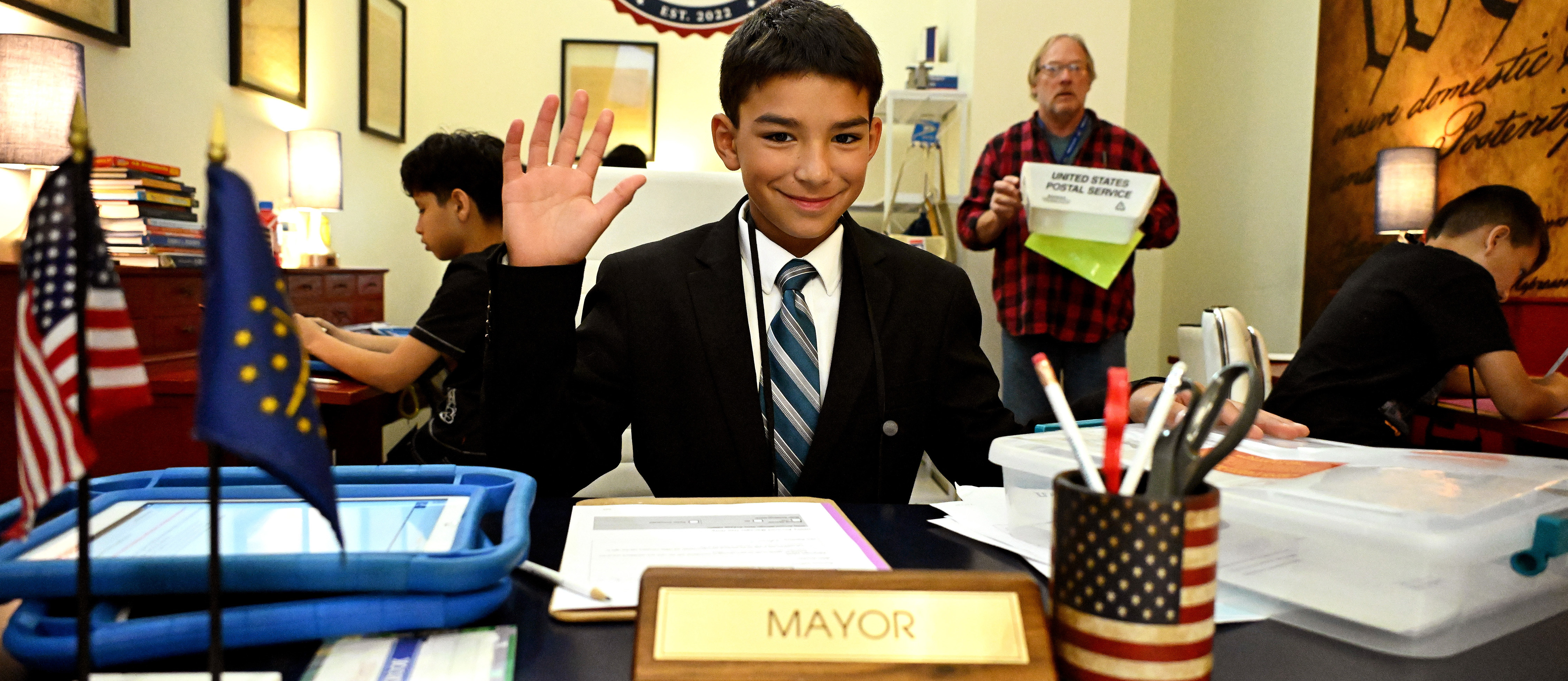a boy waving at the camera in a room at biztown