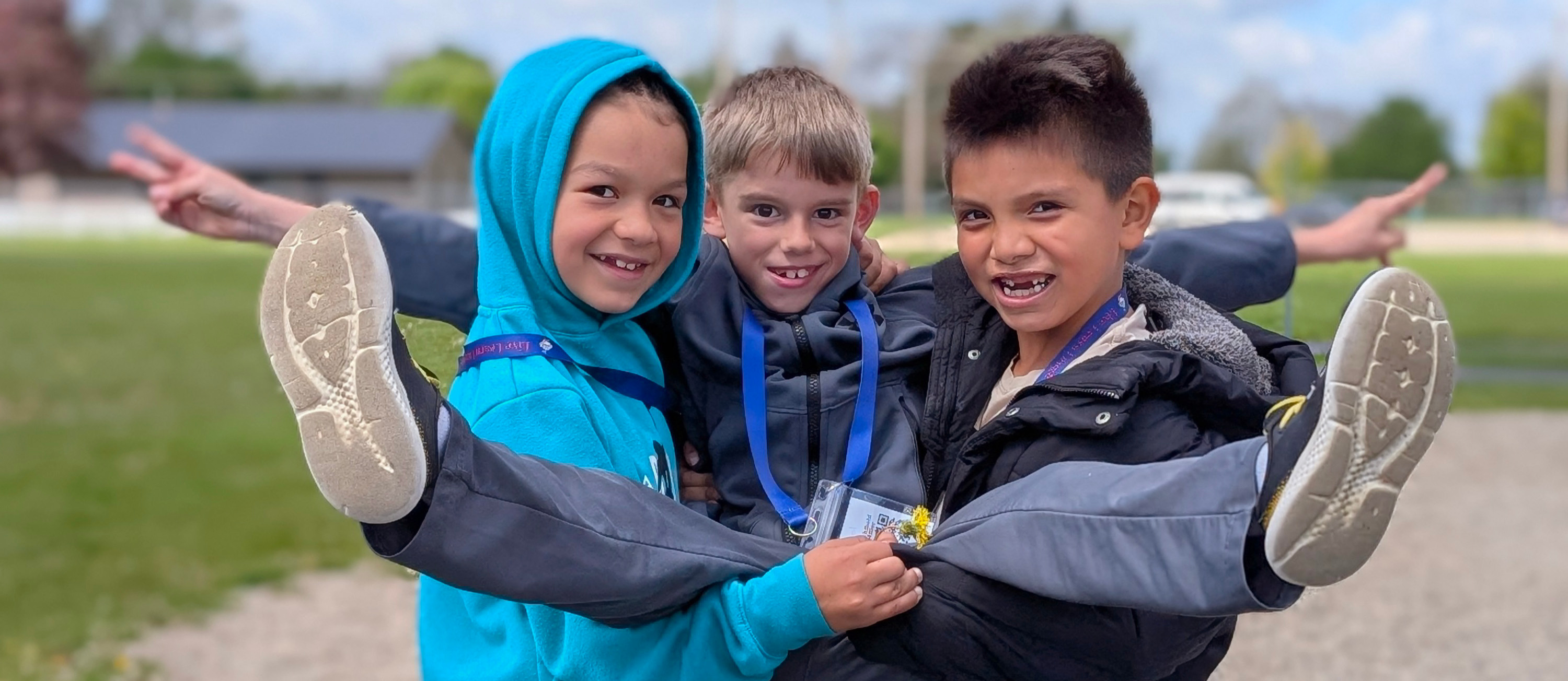 two boys holding another boy and smiling at the camera