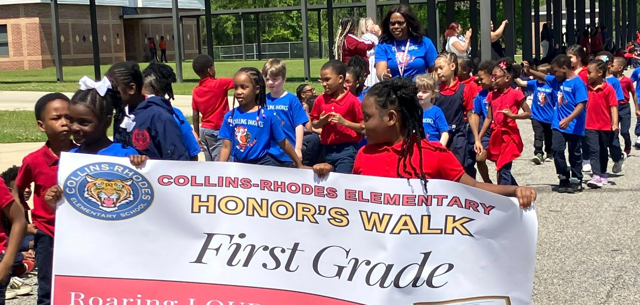 Collins-Rhodes students marching with a Honor Walk banner