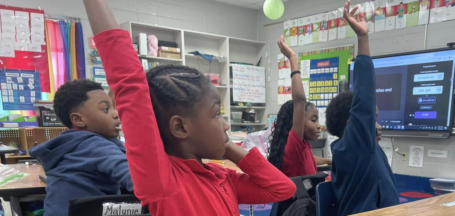 Students with hands raised in classroom