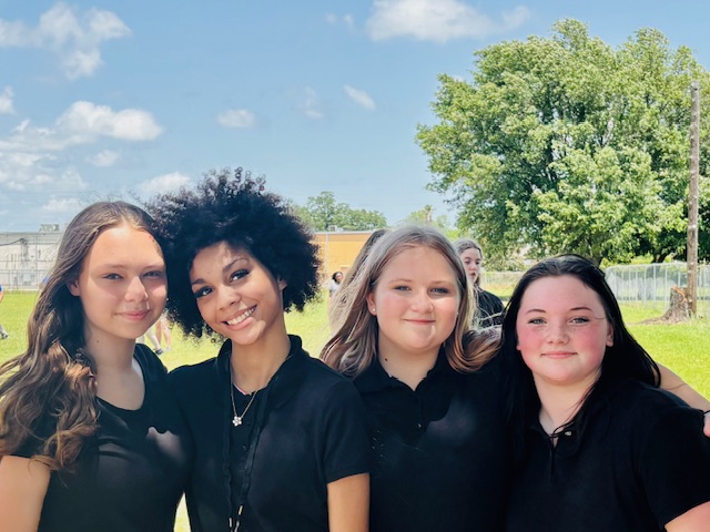 4 girls smiling  while standing outside 