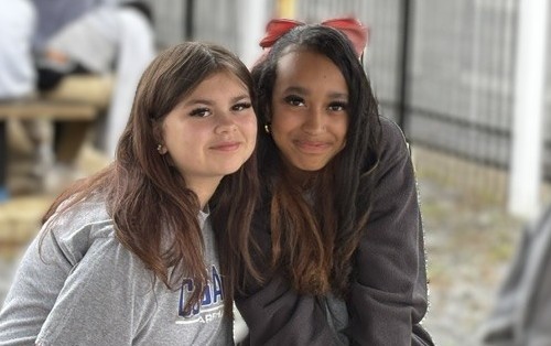 two girls smiling sitting outside the cafeteria