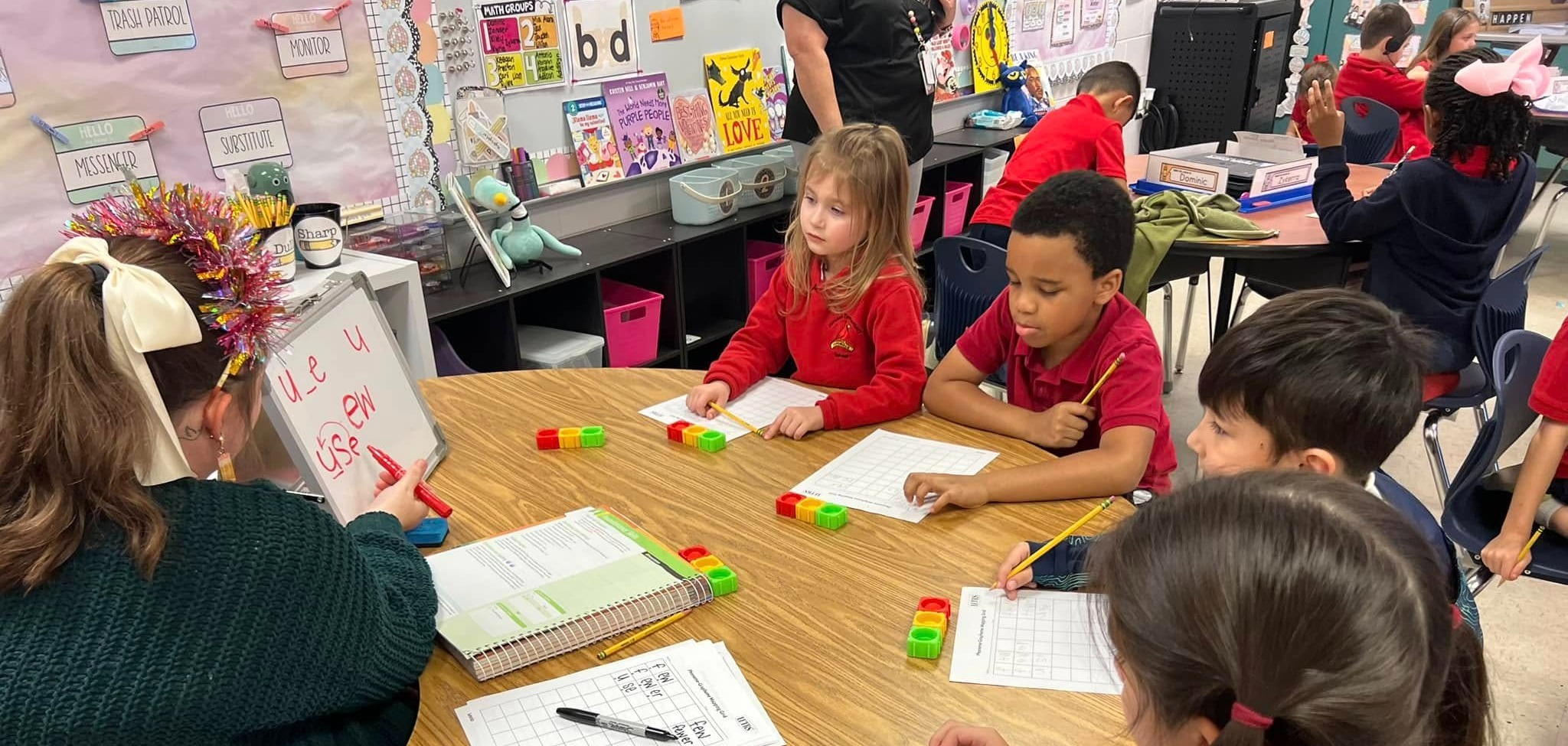 Students working with a teacher in small group on phonics skills. 