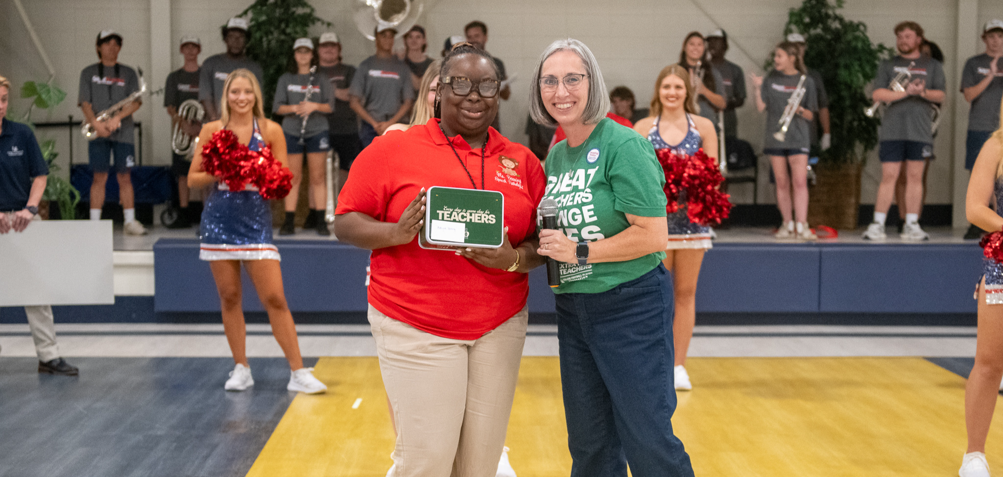 First teacher Kaliyah Benning receives a $100 grant gift card from Dr. Angela Barlow, USA College of Education, at a pep rally event.