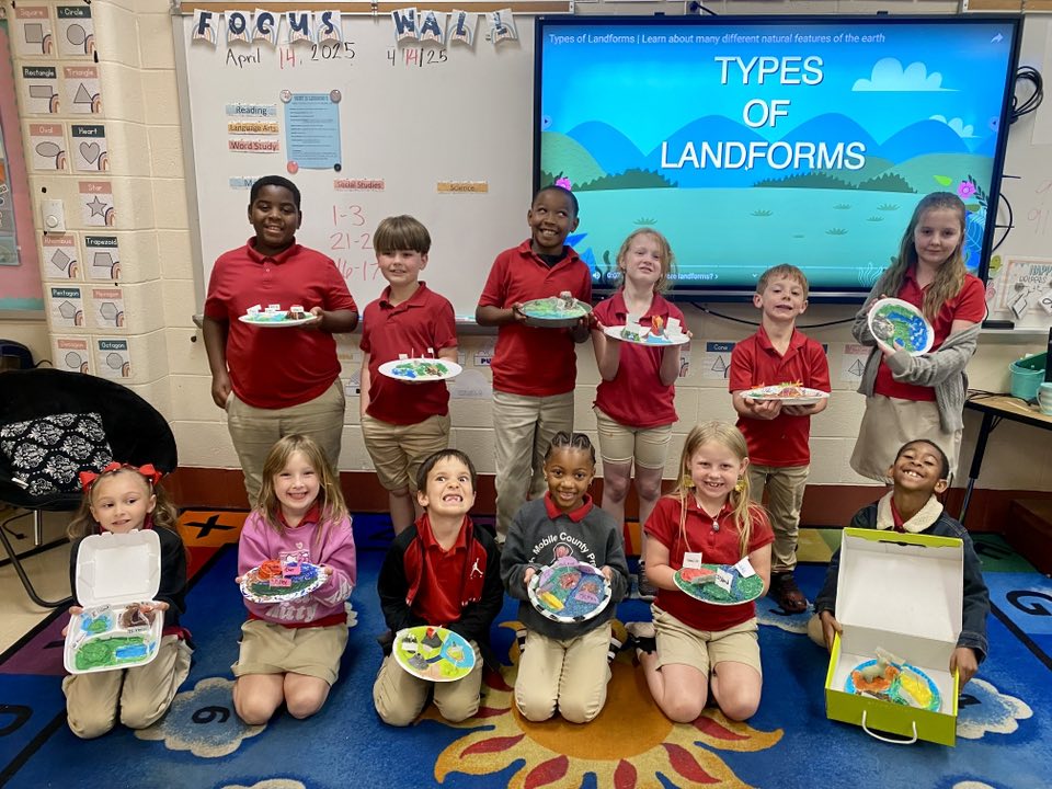 Students holding dioramas of landforms