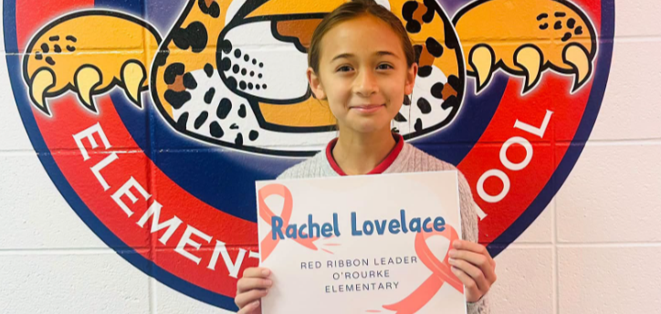 A child holding a pink sign with a cat logo in the background.