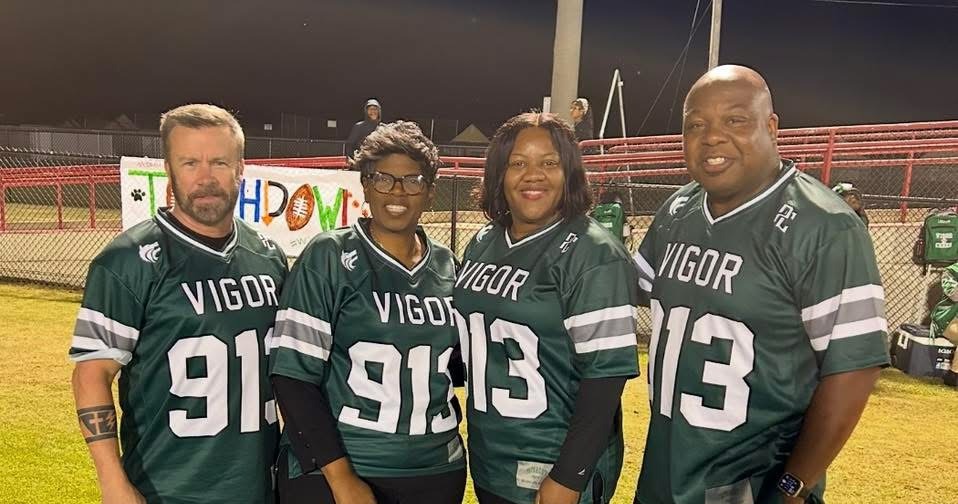 Four members of the Vigor administration standing on a football field with Superintendent Threadgill.