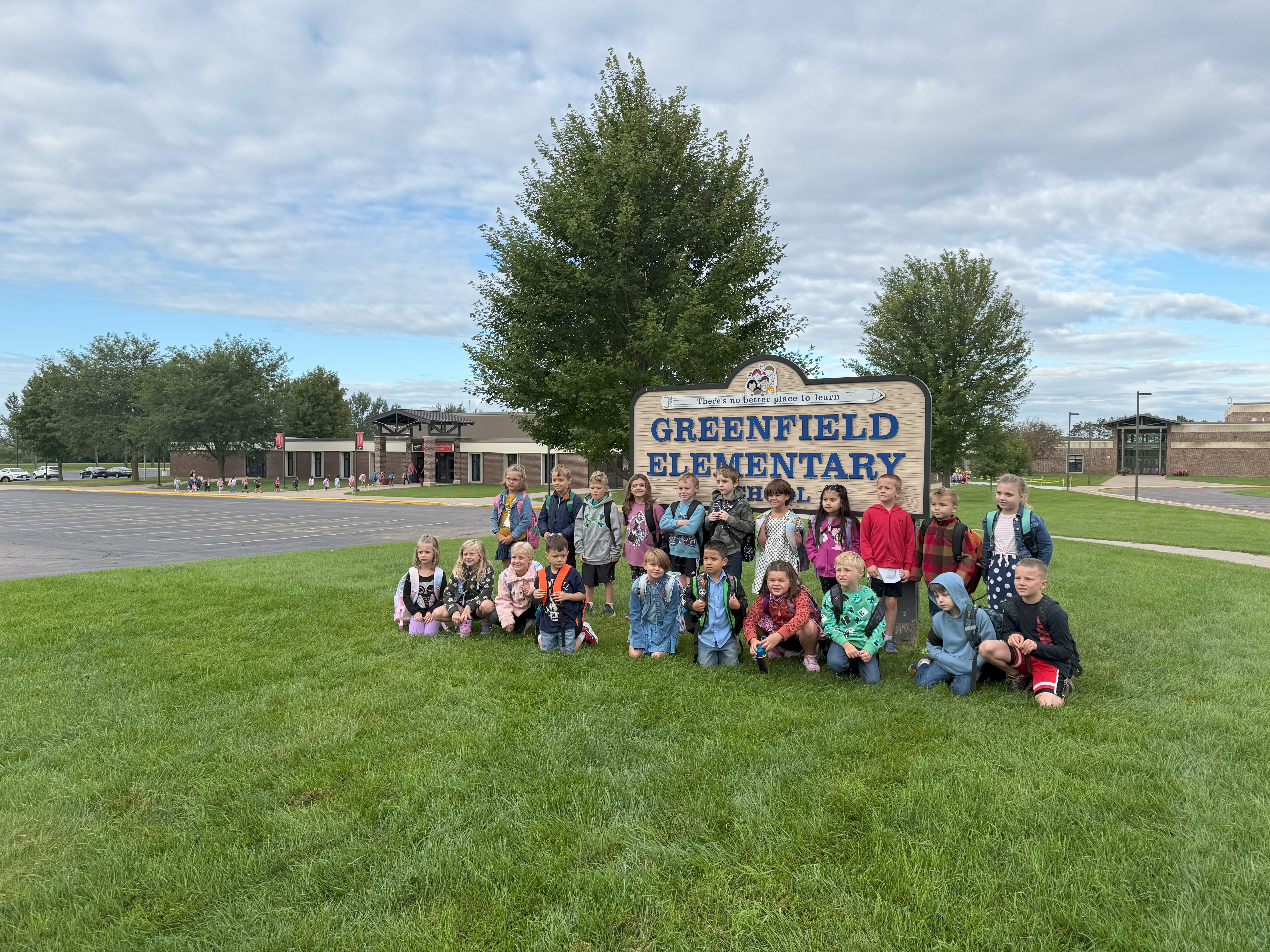 Elementary students at Greenfield Elementary School sign on the front lawn.