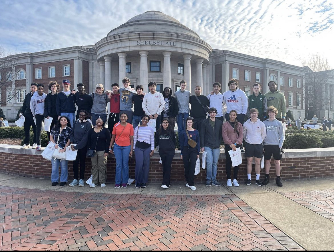 1. A group of students poses together in front of a large academic building, showcasing camaraderie and school spirit.    2. Students gather in front of a university building, smiling and engaging with one another, reflecting a vibrant campus life.    3. A diverse group of students stands proudly in front of a historic building, symbolizing unity and academic achievement.  