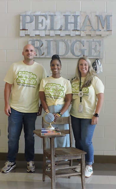 Three individuals in yellow shirts pose in front of a sign reading "Pelham Ridge."