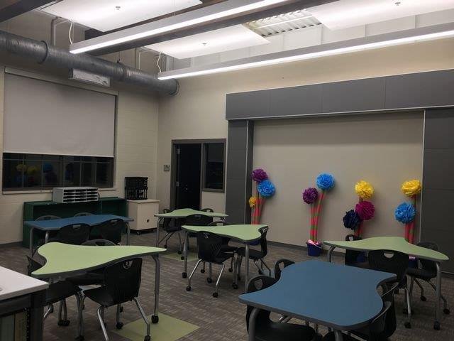 A classroom featuring neatly arranged tables and chairs, ready for students to engage in learning activities.