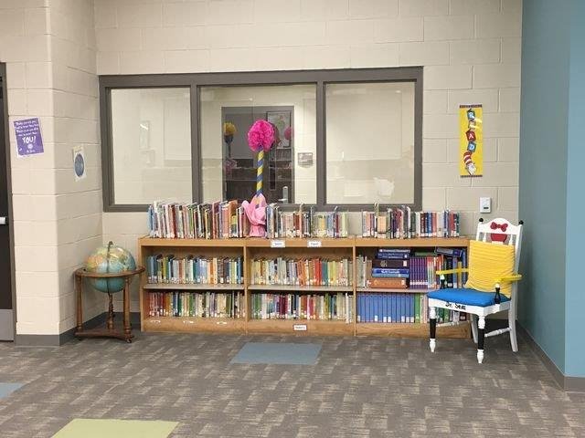 A cozy library featuring shelves filled with books and a comfortable chair positioned in front of them.