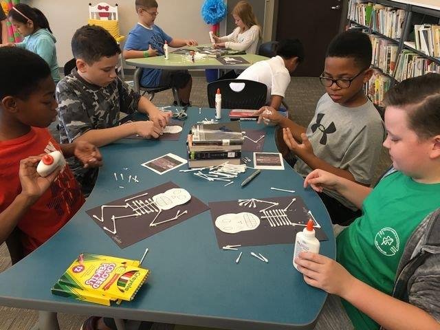 Students engaged in crafting activities at the library, showcasing creativity and collaboration in a vibrant learning environment.