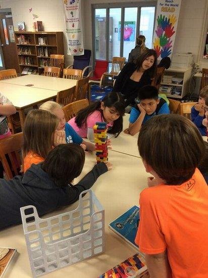 Elementary school students engaged in play, building structures with colorful blocks on the classroom floor.