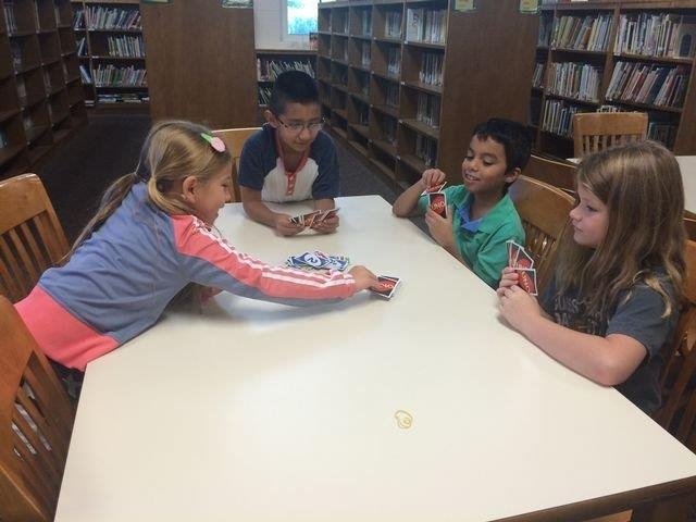 A group of students studying together in a library, surrounded by books and focused on their work.