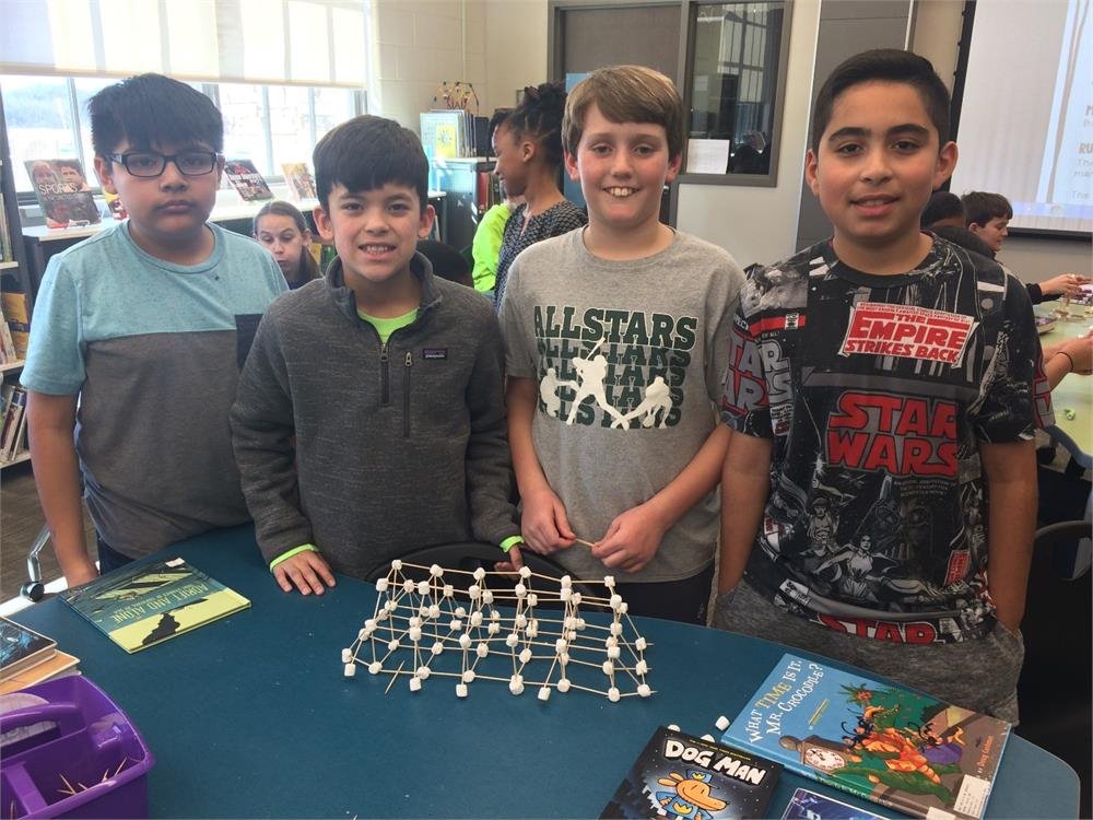 Four boys pose in front of a table, with a soccer ball prominently displayed between them.