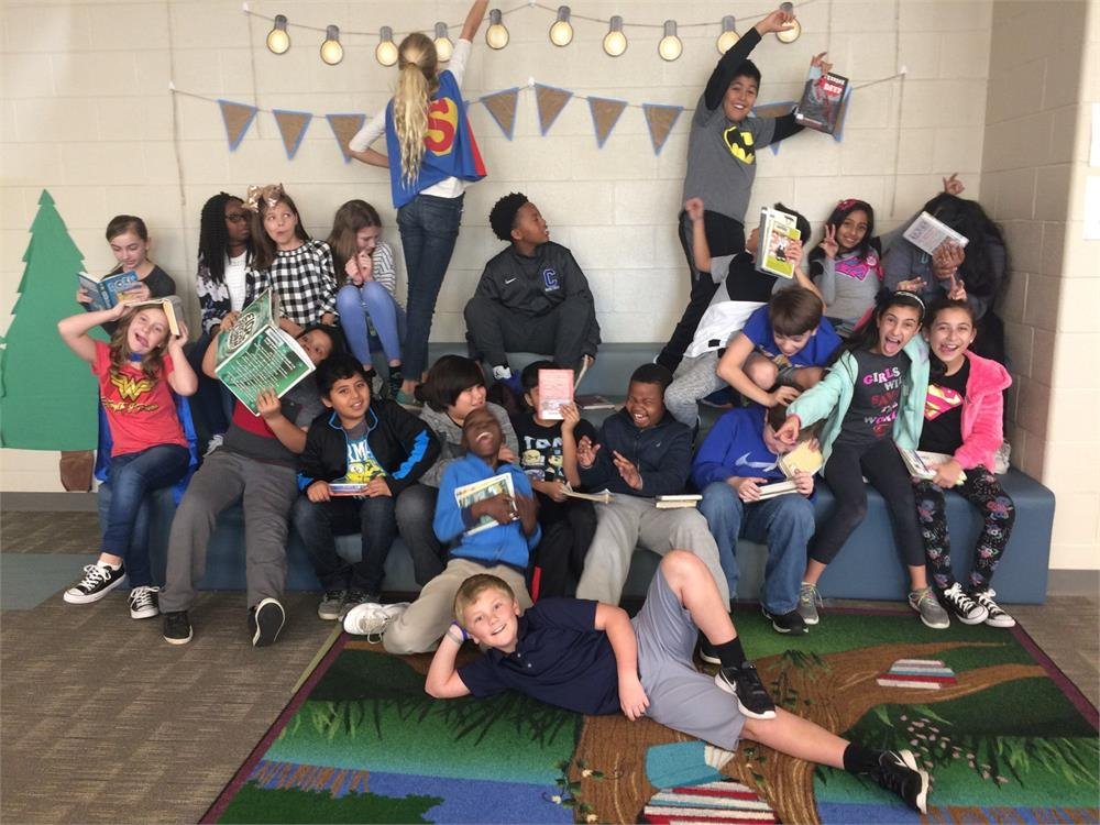 A group of children seated on a bench, each engrossed in their own books, enjoying a moment of reading together.