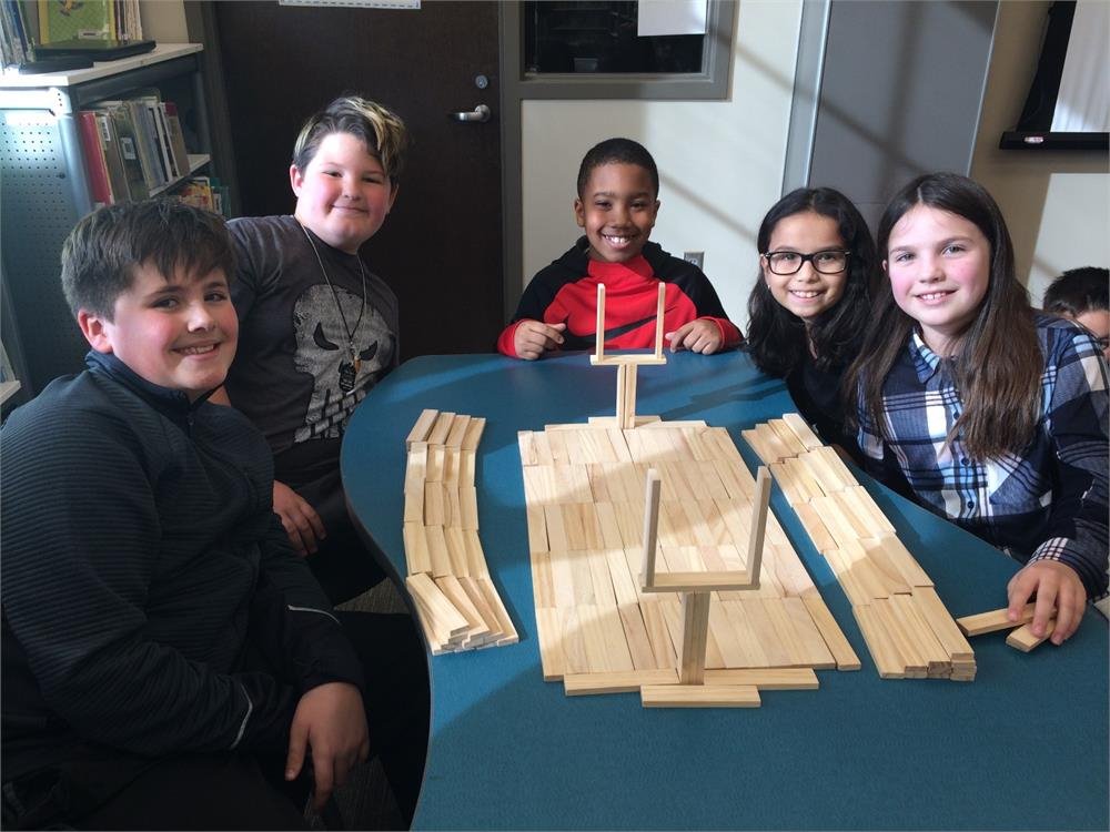 Students at the School of the Arts in New York proudly pose with their handcrafted wooden train, showcasing their creativity.