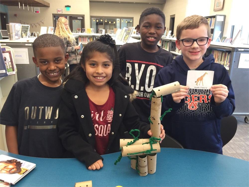 Students collaborating on a project in the library, surrounded by books and study materials.