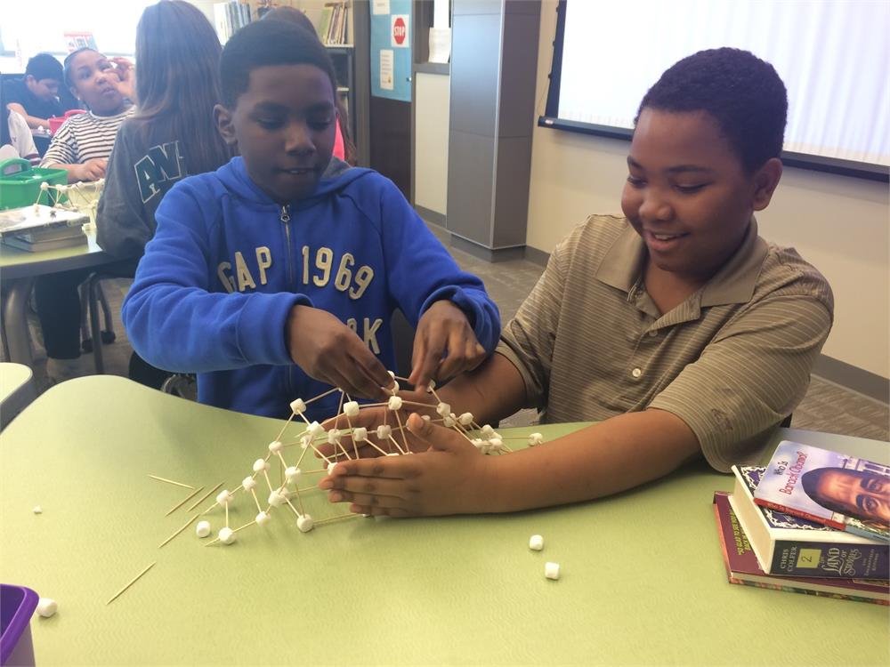 Two boys are constructing a tower using marshmallows, showcasing creativity and teamwork in a playful setting.