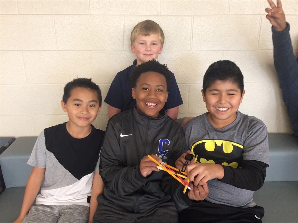 Four boys smile for a photo, each holding a Batman toy, showcasing their excitement and friendship.