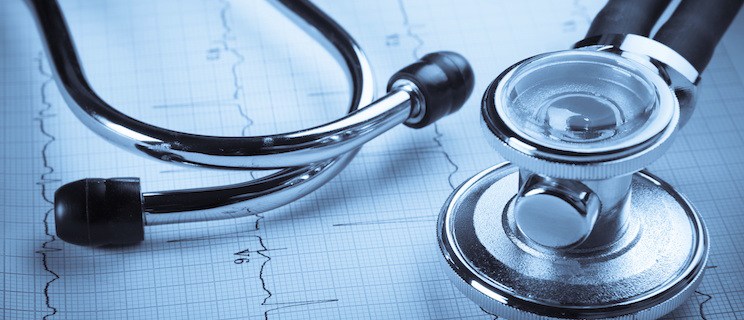 A stethoscope rests on a medical chart placed on a wooden table, symbolizing healthcare and patient assessment.