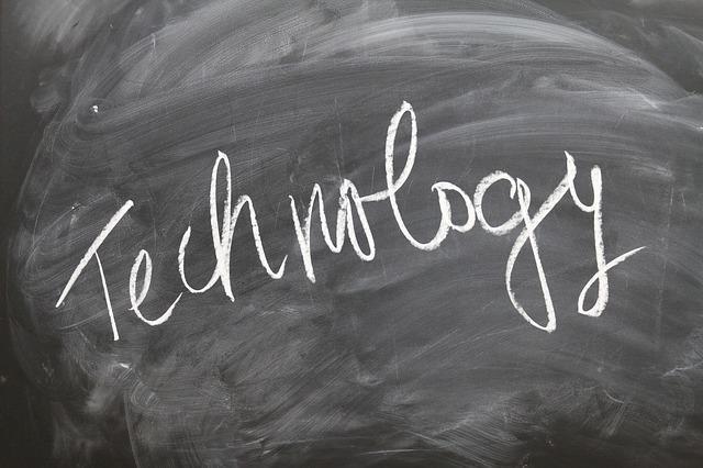 A blackboard displays the word "technology" in white chalk, emphasizing a classroom or learning environment